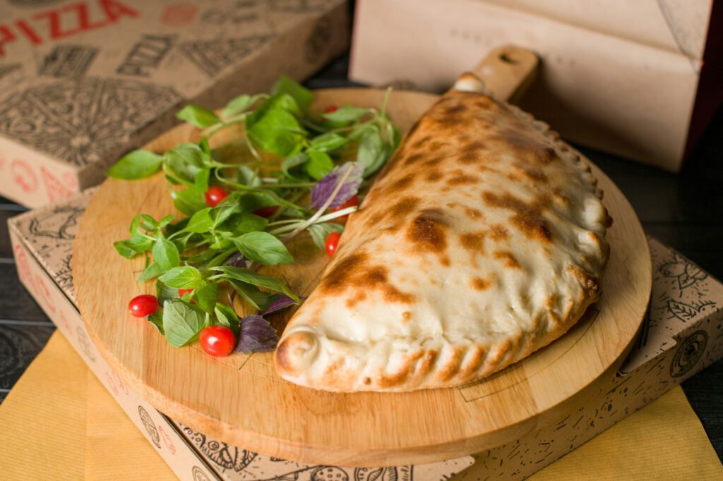A delicious calzone sits on a wooden board.
